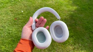 Sonos Ace noise-cancelling headphones held in hand showing inside of earcups against background of grass