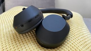Sony WH-1000XM5 headphones on a yellow cushion